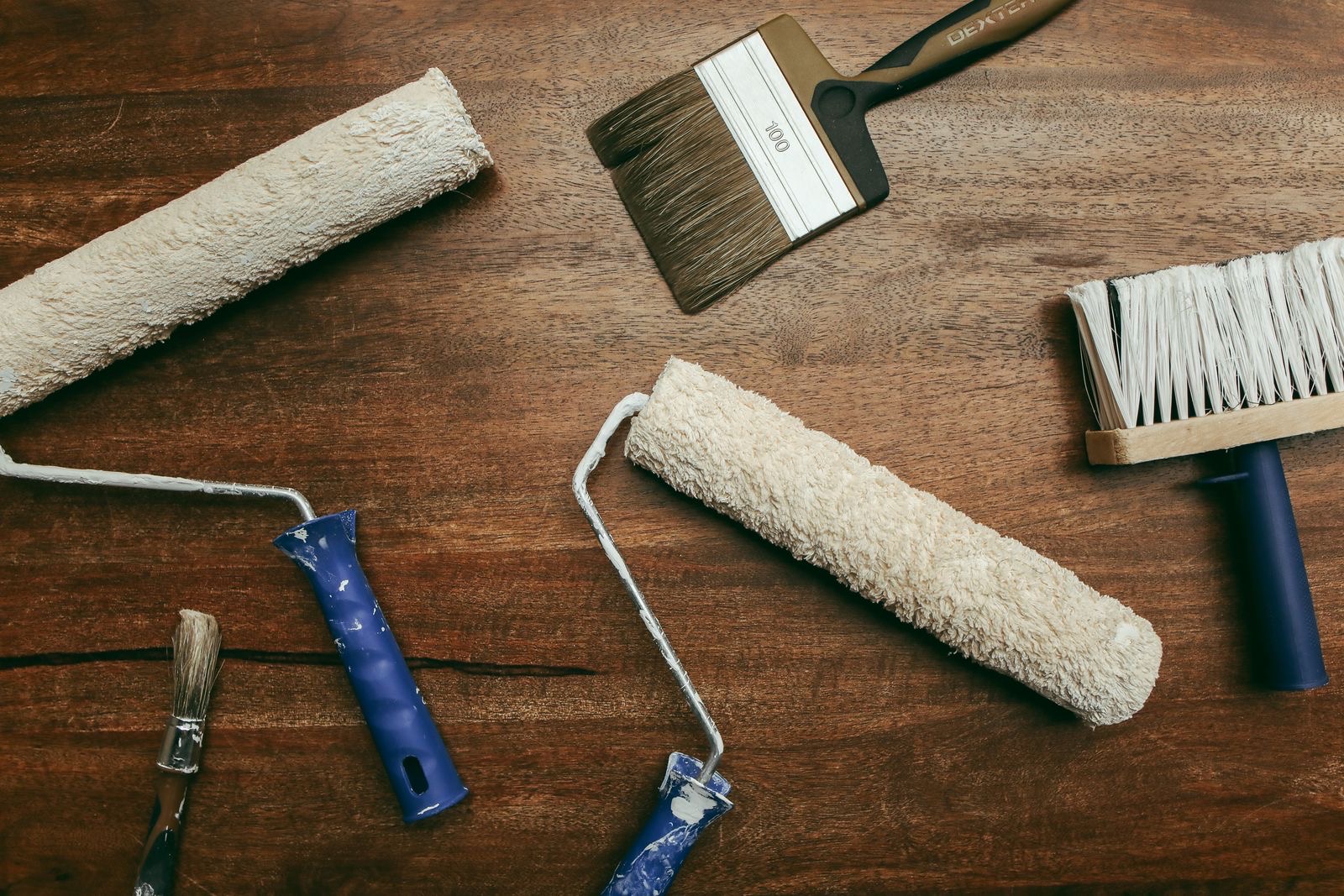 Close-up of a decorator's tool roll with brushes, filler knife, and sandpaper laid out