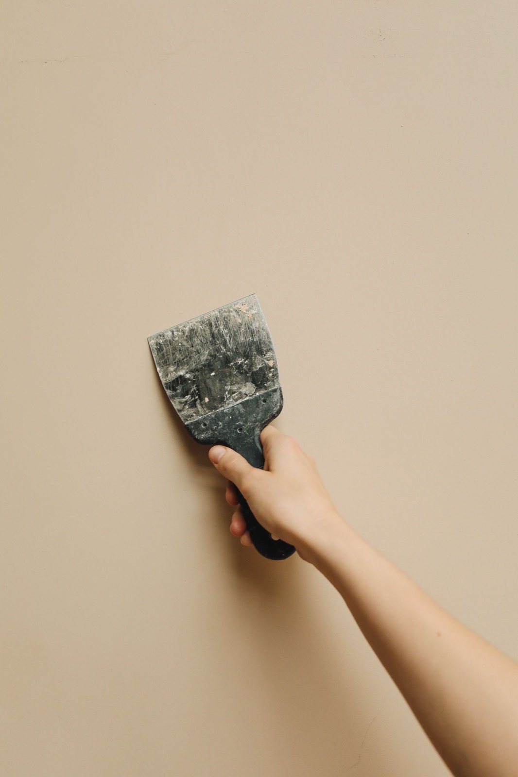 Close-up of a decorator filling and sanding a wall smooth before painting