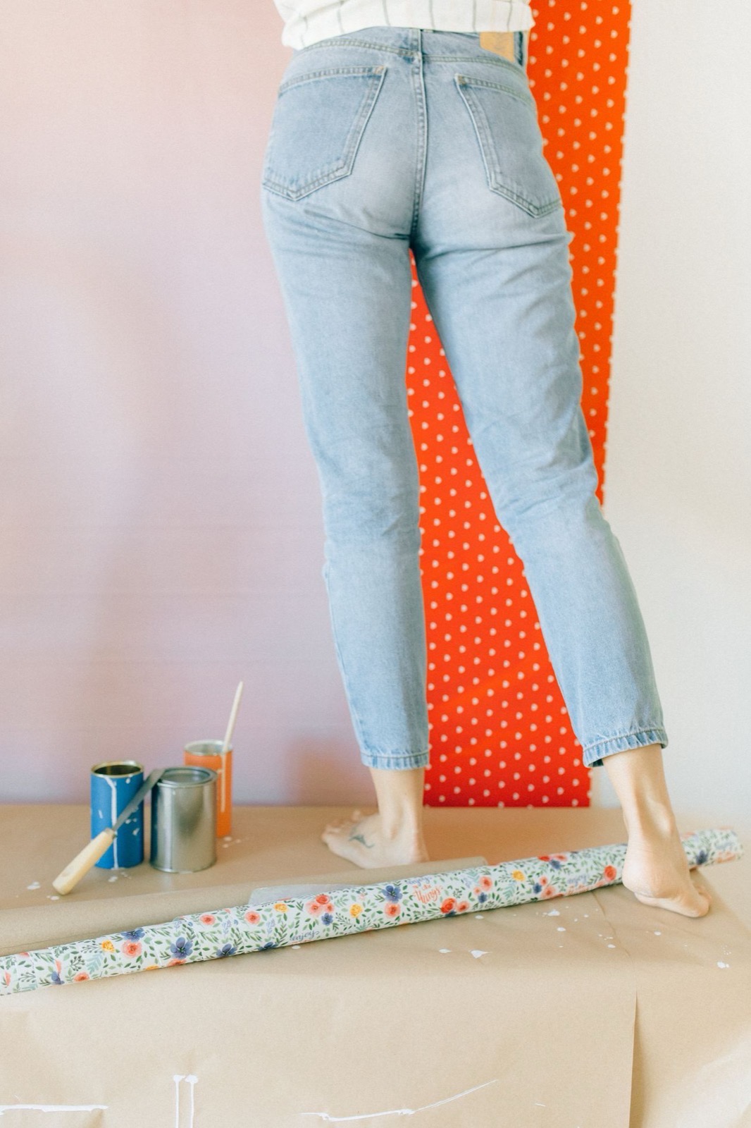 A rolled length of wallpaper and paint tins laid out on a covered table, ready for a job